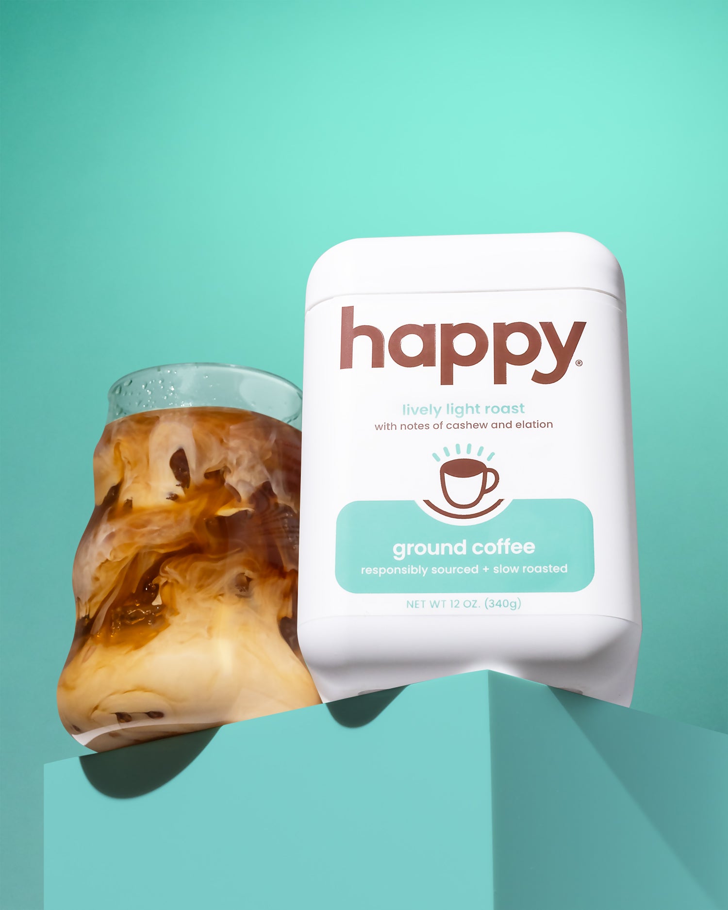 White container of 'happy' ground coffee with an iced coffee on a teal background