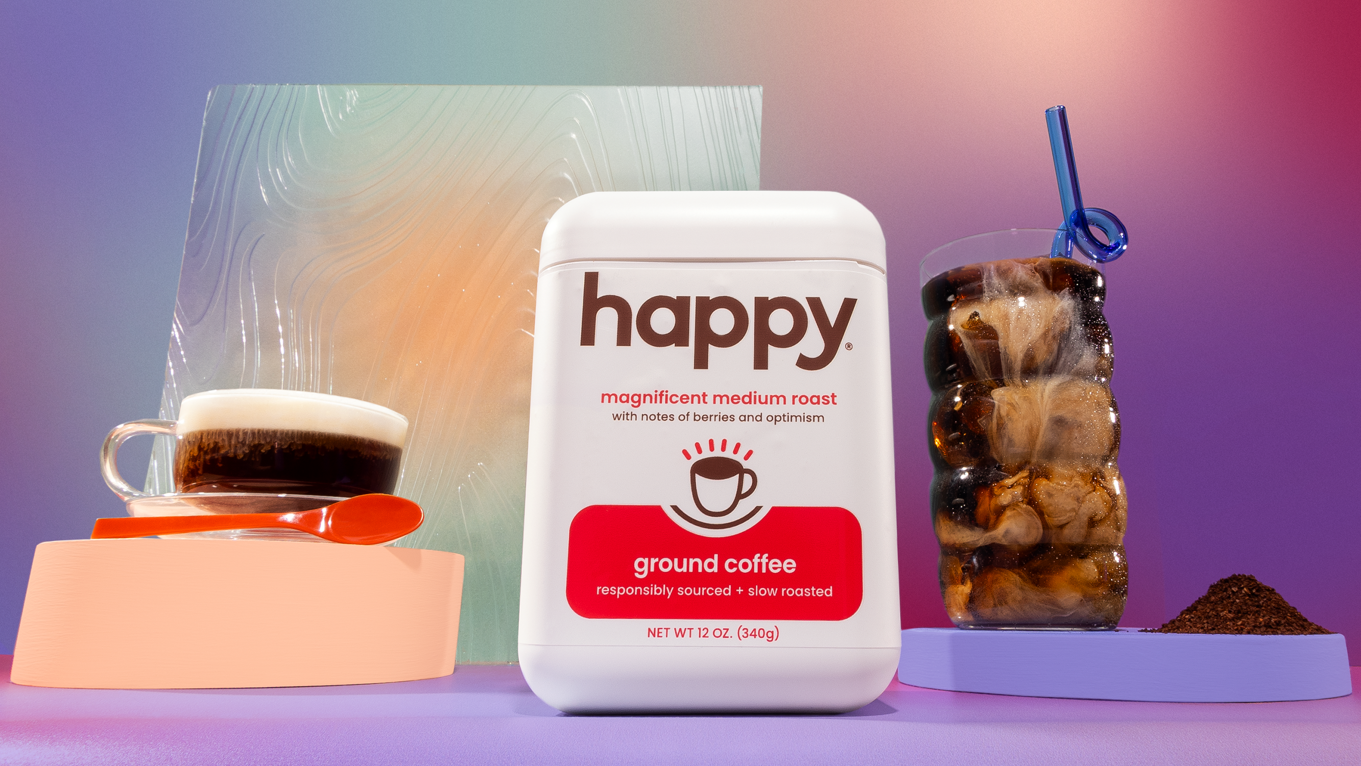 Container of 'happy' medium roast ground coffee with two mugs of coffee next to it on a gradient background