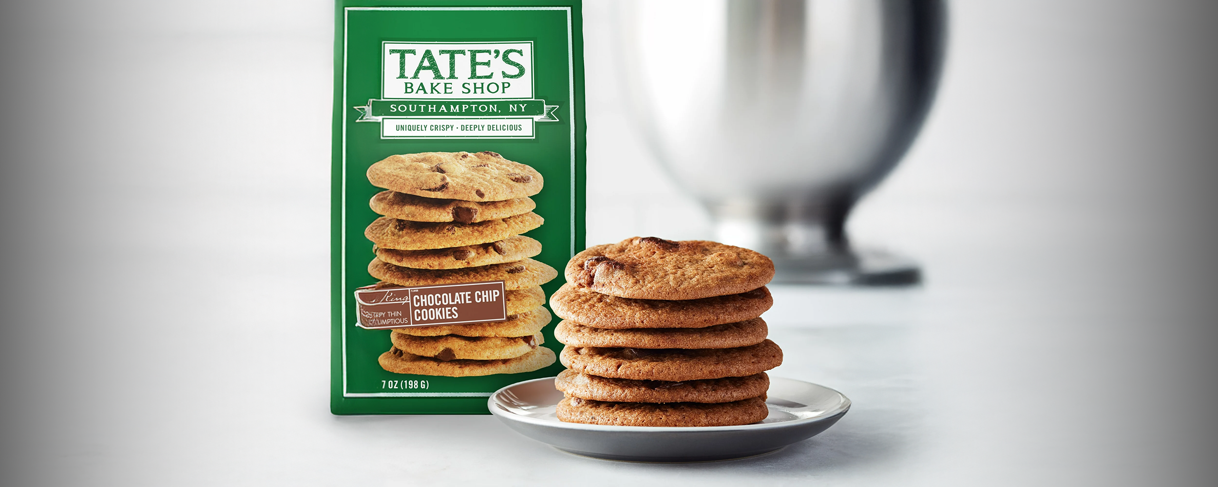 Tate's Bake Shop chocolate chip cookies on a white table with a bowl in the background