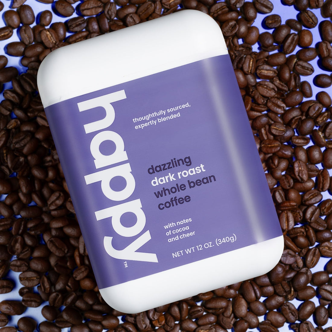 Whole Bean Dazzling Dark Roast Coffee container resting on a bunch of coffee beans