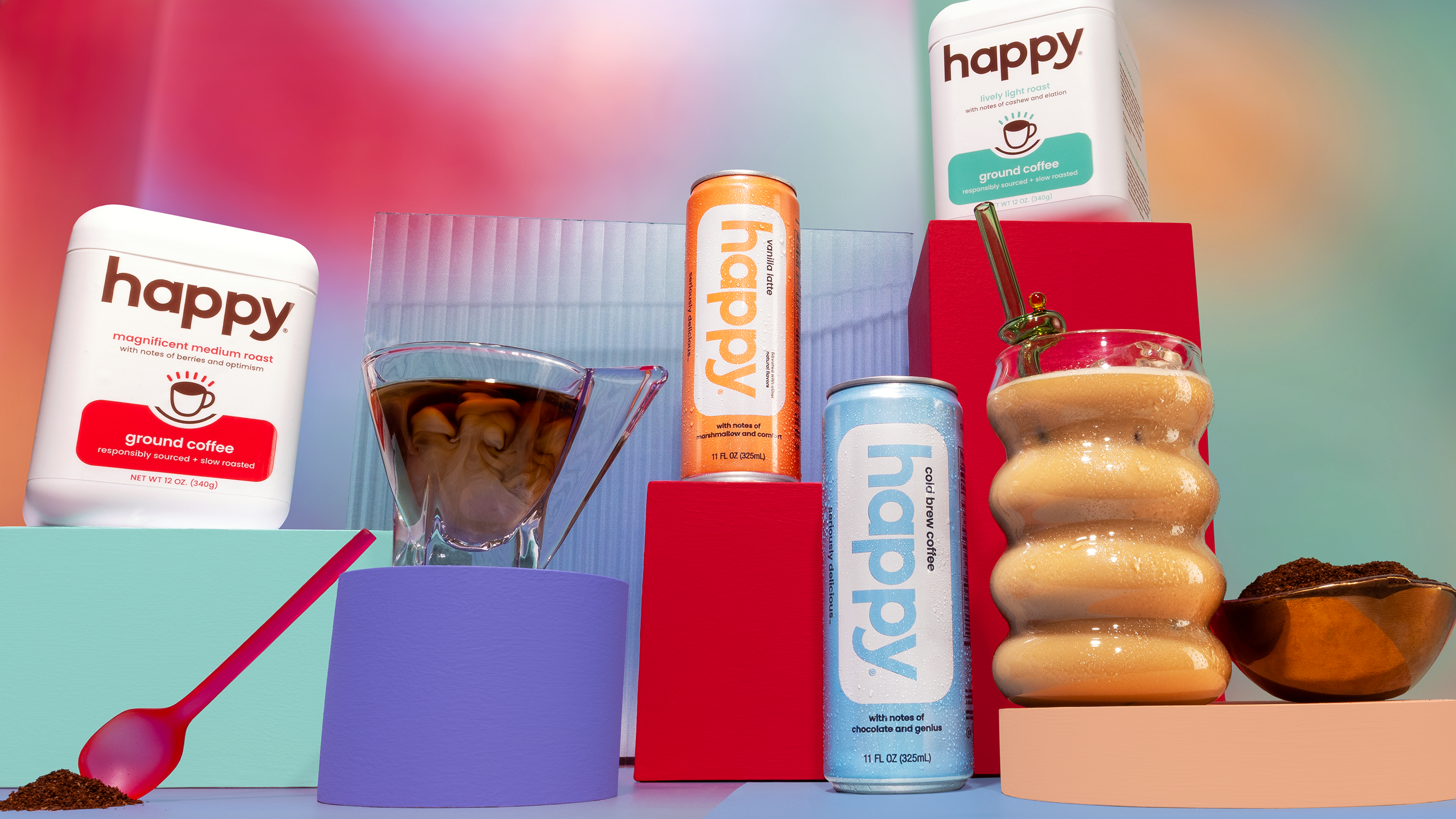 happy ground coffee and happy canned cold brew and latte with cups of coffee and coffee grounds on a colorful background
