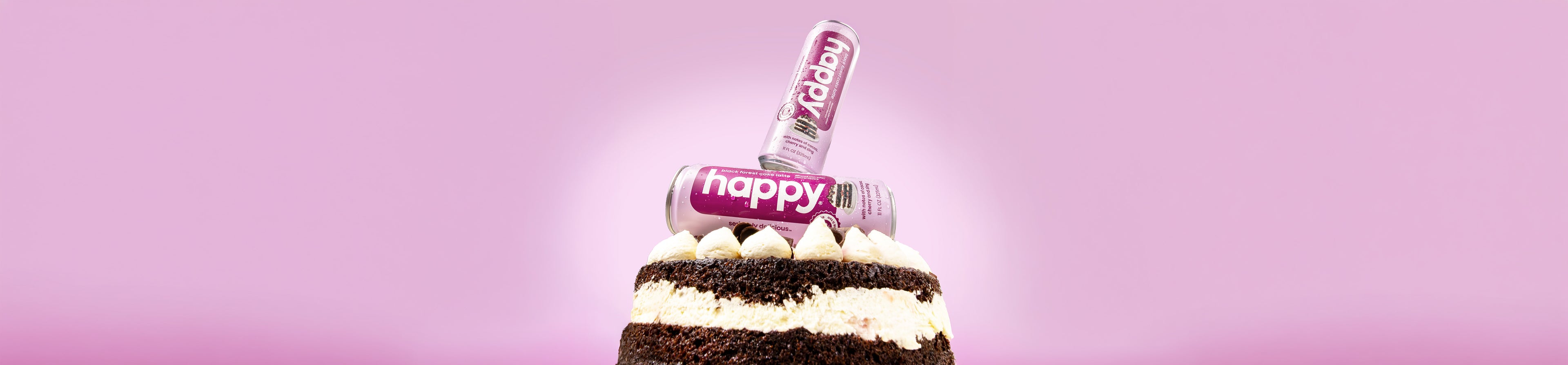 2 Cans of 'happy black forest cake latte with a cake on a purple background