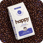 A bag of Happy Brand dark roast ground coffee placed on top of a dense bed of whole coffee beans. The bag is white with blue and brown text and graphics, and the background consists entirely of roasted coffee beans.