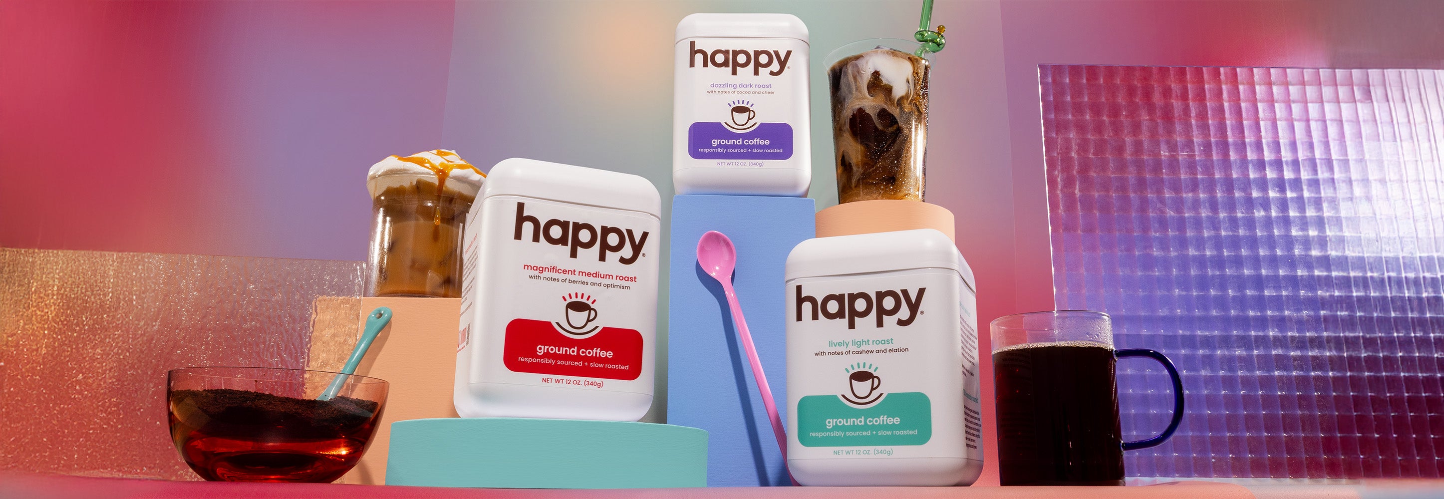 three happy coffee containers  on a colorful background with a glass of coffee and a bowl of coffee grounds.