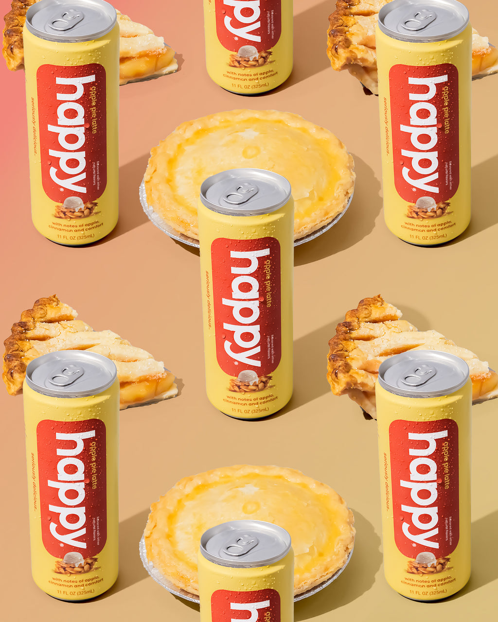 Yellow 'happy' apple pie cans with on a peach background with slices of apple pie.