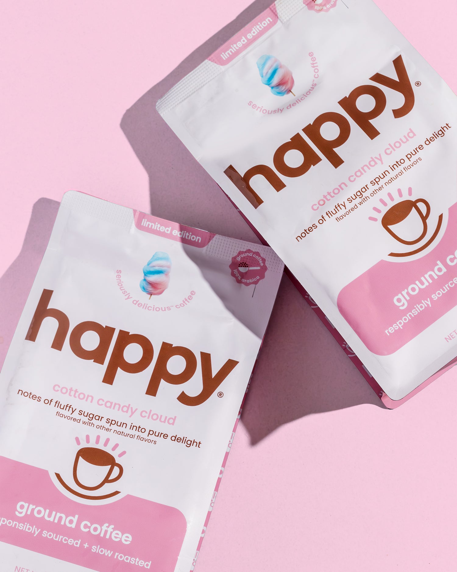 two packages of happy cotton candy cloud coffee laying down on a pink table