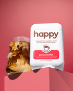 White 'happy' coffee package with a pink background