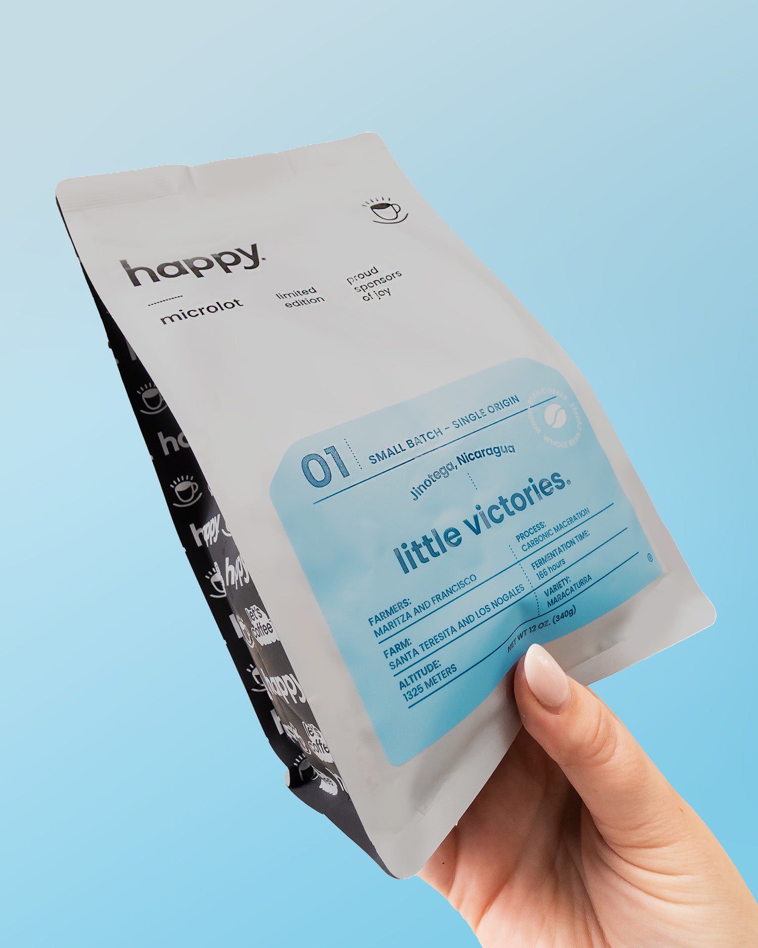 Hand holding a 'little victories' coffee product package against a light blue background