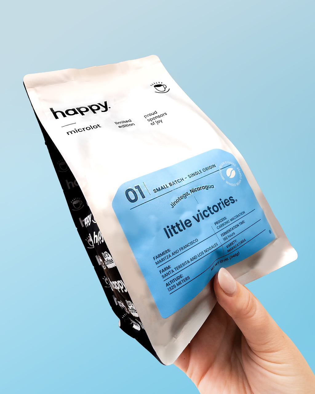 Hand holding a 'little victories' speciality Nicaraguan coffee package against a light blue background