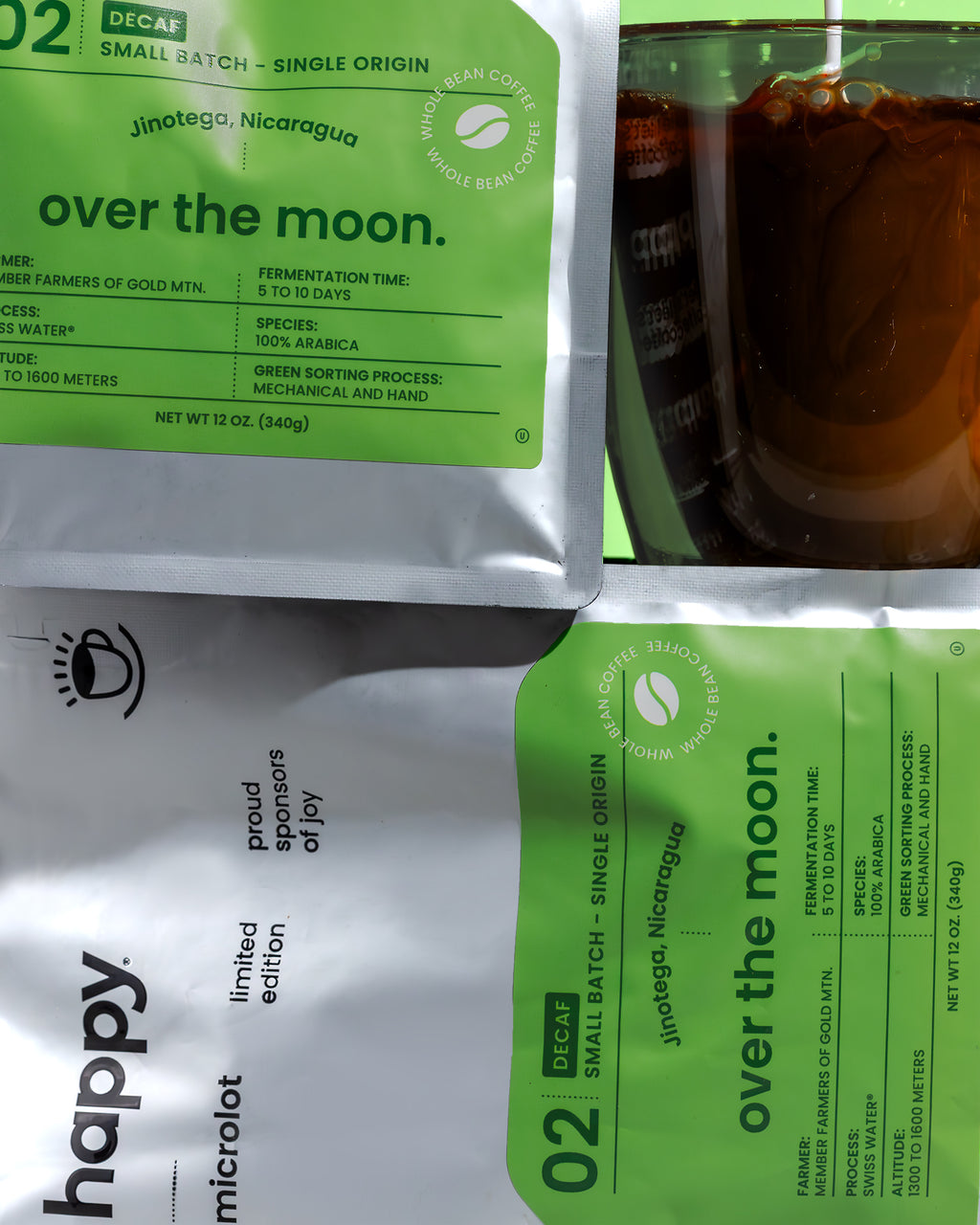 Over the Moon Decaf Coffee bag on its side with coffee, from happy on a green background