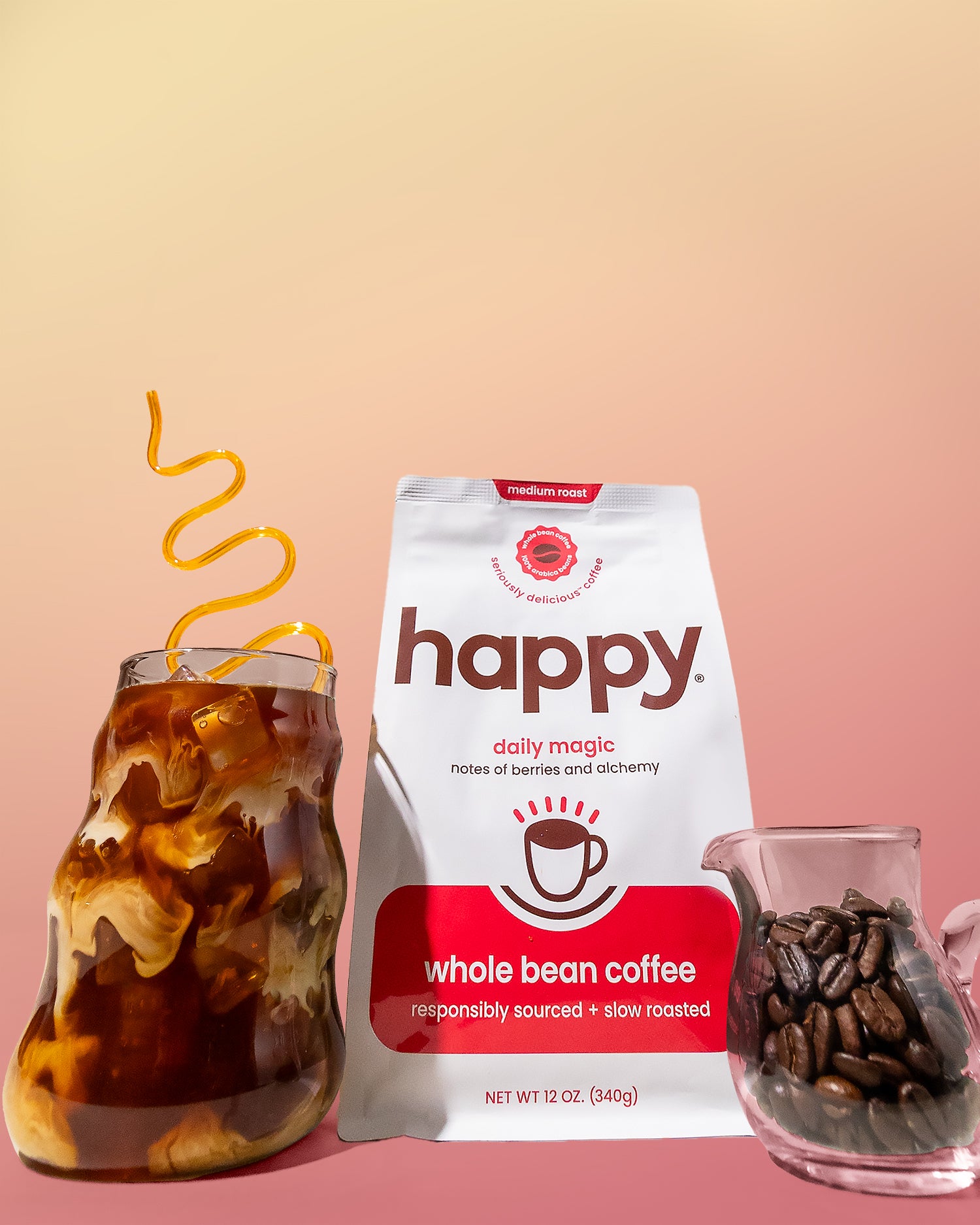 Happy whole bean coffee package with iced coffee and coffee beans on a pink background
