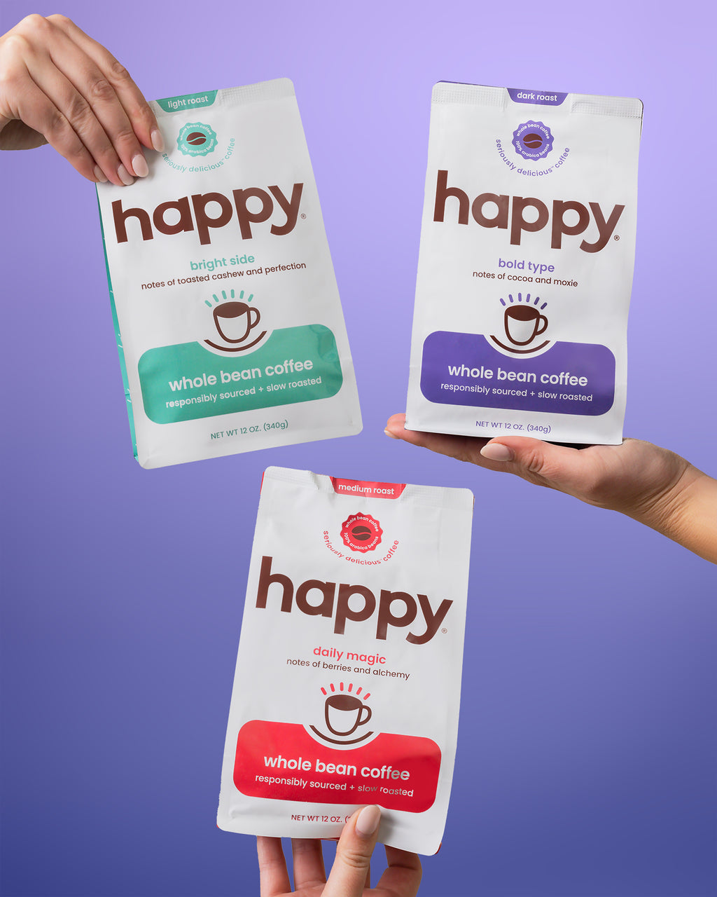 Three 'happy' brand whole bean coffee packages held by hands against a purple background