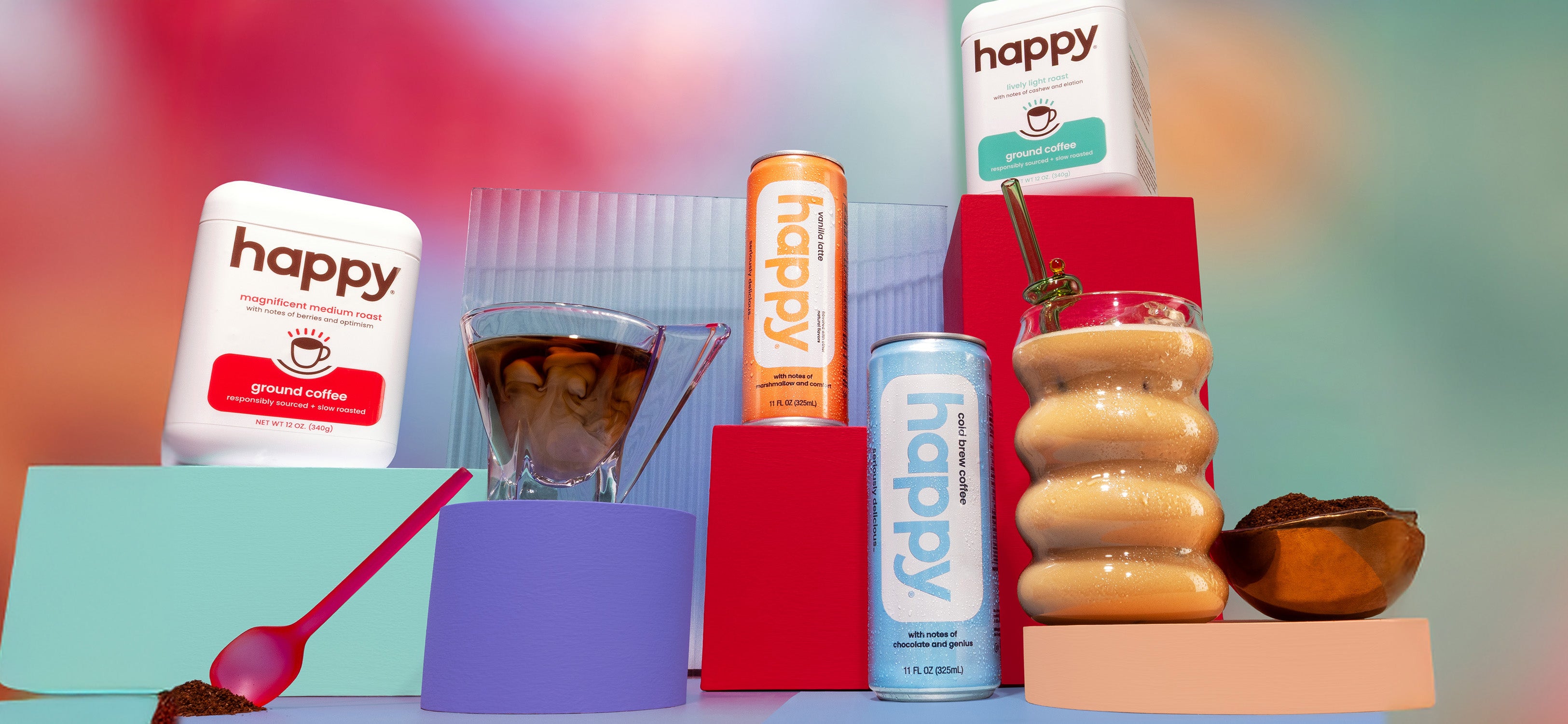Assorted 'happy' branded products including a can, a bottle, a glass with a straw, and a bowl on a colorful background.