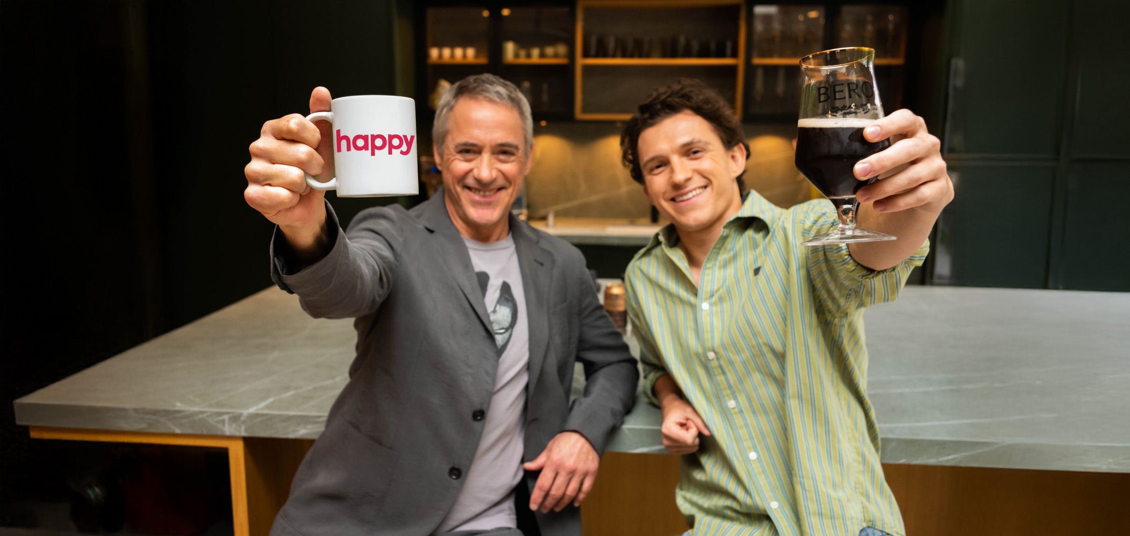 Robert Downey Jr and Tom Holland holding up a Happy Coffee and a Non Alcoholic BERO Happy Coffee Draught. Both are smiling and hoping you will drink their collab
