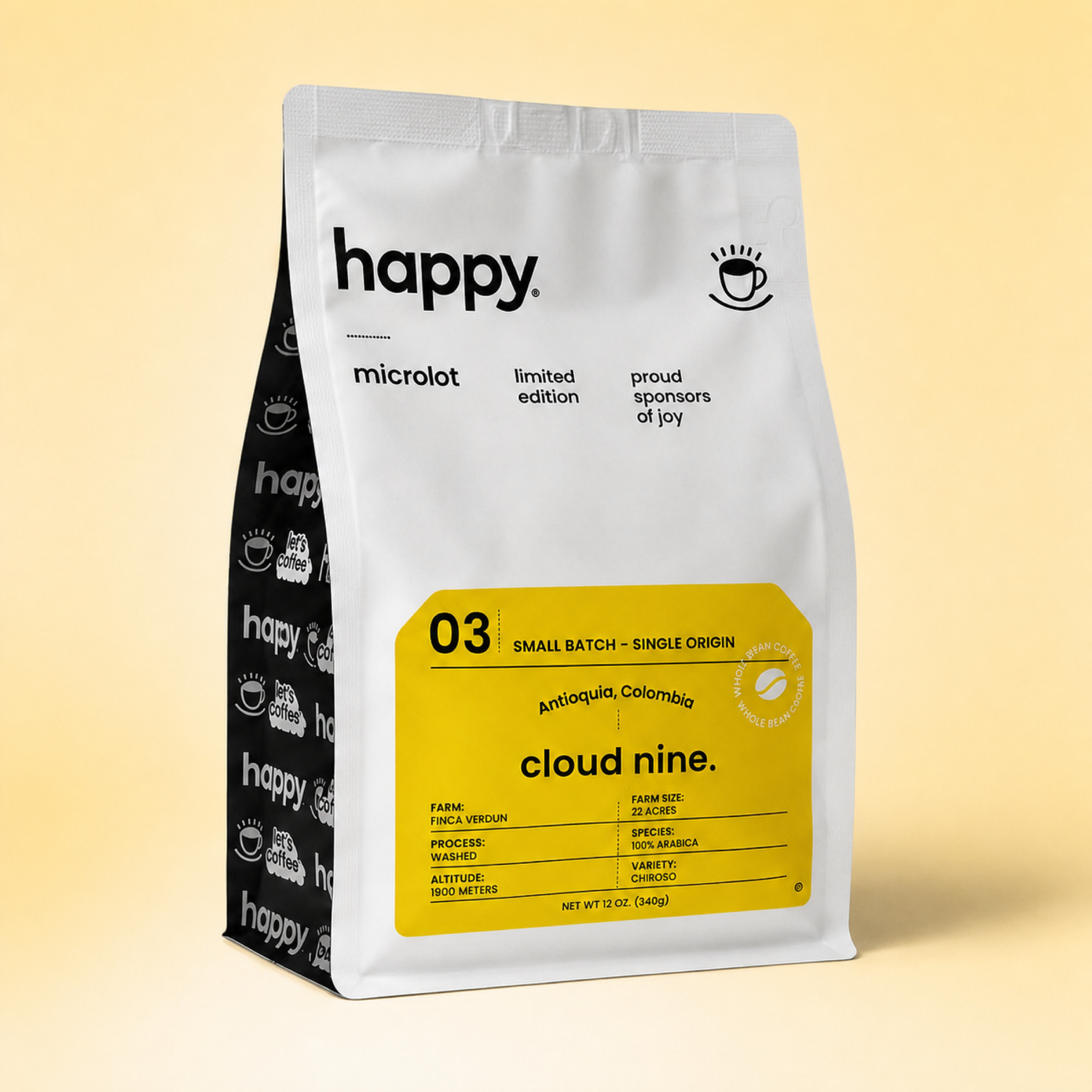 A stand-up coffee bag from Happy Microlot, featuring a silver front with a large yellow label and a black side panel with repeated coffee cup logos, photographed on a warm beige gradient background.
