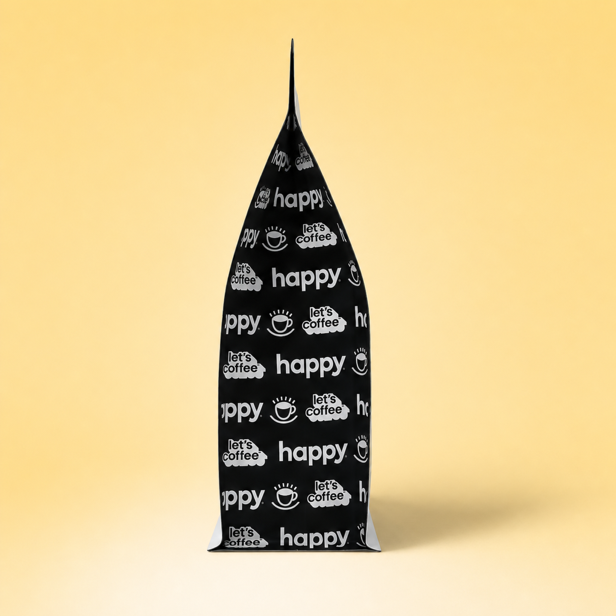 A Side view of Happy Cloud Nine Microlot Coffee showing black side bag with a white repeating pattern of 'happy' text, coffee cups, and let's coffee™, standing upright on a light beige gradient background.